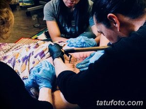 Фото процесса нанесения татуировки, демонстрирующее работу мастера и концентрацию на деталях рисунка.